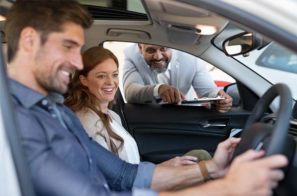Salesman showing car to couple